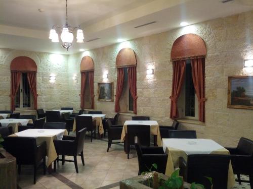 a restaurant with tables and chairs and red curtains at Alhambra Palace Hotel Suites - Ramallah in Ramallah