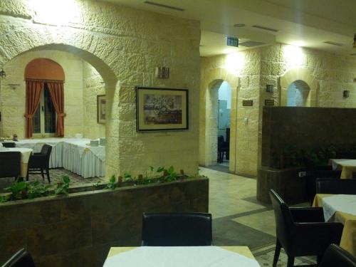 a restaurant with tables and chairs in a room at Alhambra Palace Hotel Suites - Ramallah in Ramallah