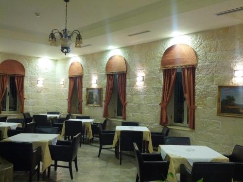 a dining room with tables and chairs and windows at Alhambra Palace Hotel Suites - Ramallah in Ramallah