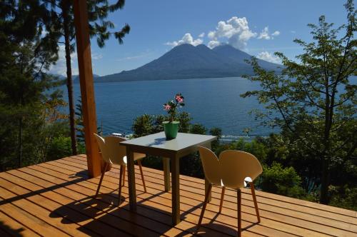 a table and chairs on a deck with a view of the water at Anzan Atitlan in San Marcos La Laguna