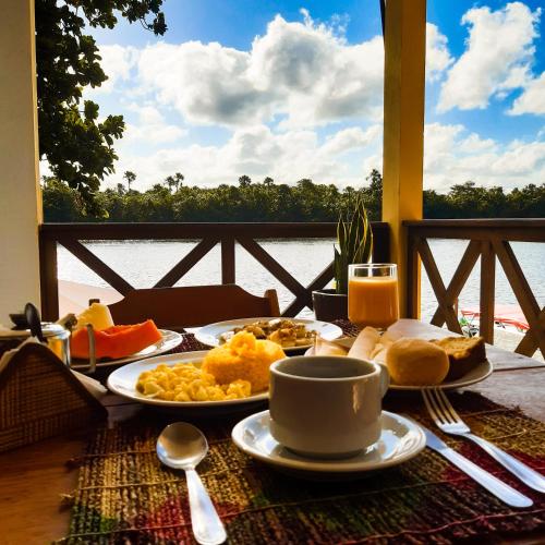 a table with breakfast food and a view of the water at Pousada Do Porto in Barreirinhas