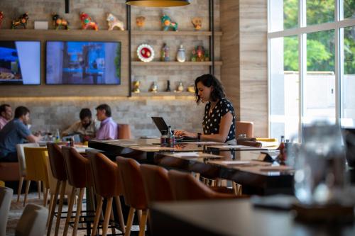 a woman sitting at a table with a laptop in a restaurant at Casa Andina Premium San Isidro in Lima