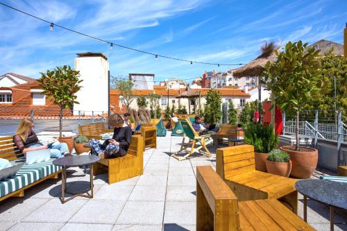 personnes assises sur des bancs sur un toit-terrasse dans l'établissement Selina Secret Garden Lisbon, à Lisbonne