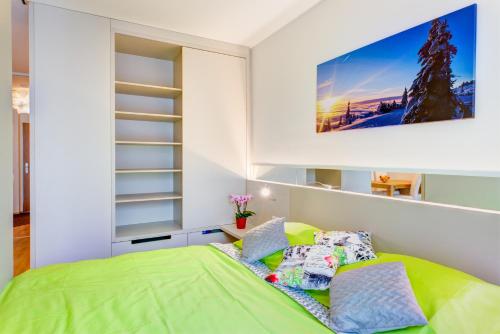 um quarto com uma cama verde e uma televisão na parede em Apartman Medvědín 307 em Spindleruv Mlyn