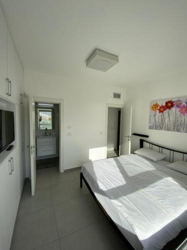 a white bedroom with a bed and a television at SeaScape Terraces Netanya in Netanya