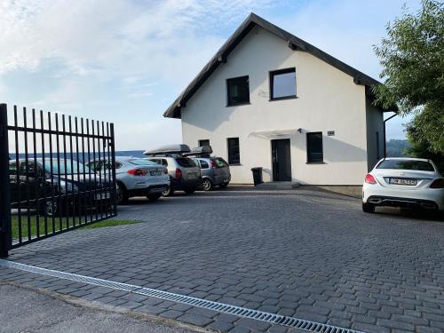 a white house with cars parked in a parking lot at Willa Hańcza 1 in Kleszczówek