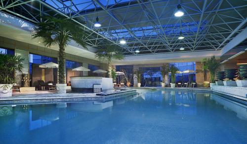a large swimming pool with palm trees in a building at Grand Mercure Xian On Renmin Square in Xi'an