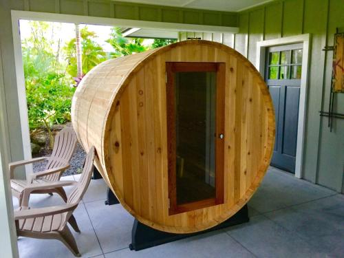 a round wooden sauna on a porch with a chair at Pua Lani in Keaau