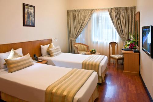 a hotel room with two beds and a television at Landmark Plaza Hotel in Dubai