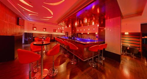 a bar with red bar stools in a room at Gokulam Park Coimbatore in Coimbatore