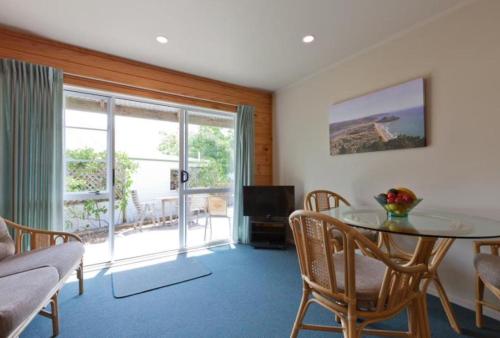 a living room with a glass table and chairs at Pauanui Pines Motor Lodge in Pauanui