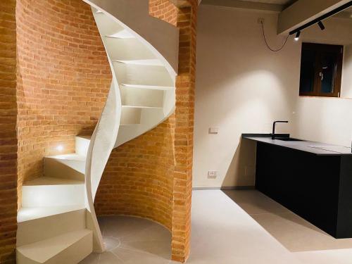 uma escada em espiral numa cozinha ao lado de uma parede de tijolos em Agriturismo PURO em Barga