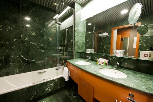 a bathroom with two sinks and a large mirror at Gran Hotel Lakua in Vitoria-Gasteiz