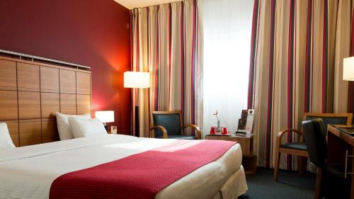 a hotel room with a bed and chairs and a window at Holiday Inn Bordeaux Sud - Pessac by IHG in Pessac