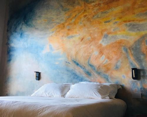 Agriturismo PURO في بارغا: غرفة نوم مع لوحة على الحائط بجانب سرير