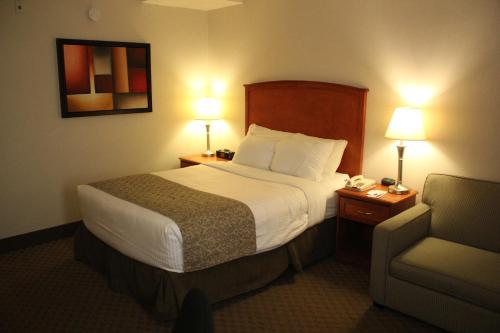 a hotel room with a bed and a chair at Ramada by Wyndham Edmonton South in Edmonton