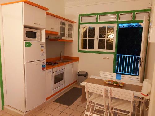 a kitchen with a white refrigerator and a table at Bungalow PAPAYE in Pointe-Noire