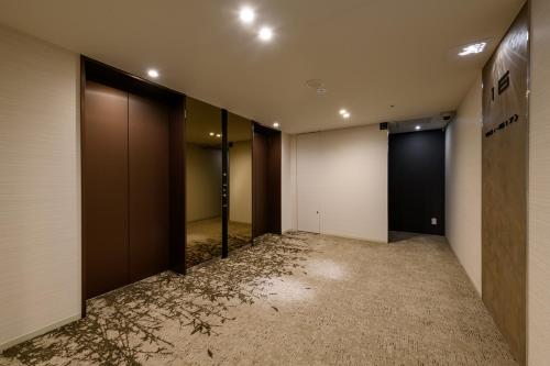 an empty hallway with a row of elevators in a building at remm plus Ginza in Tokyo