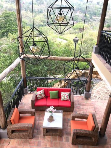 a patio with a red couch and chairs on a balcony at Hotel Casas de Campo El Ciruelo in San Gil