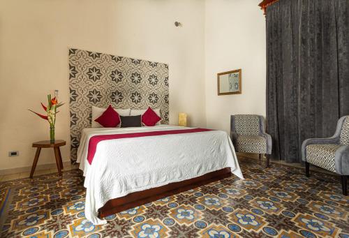 a bedroom with a large bed with red pillows at Viva Merida Hotel Boutique in Mérida