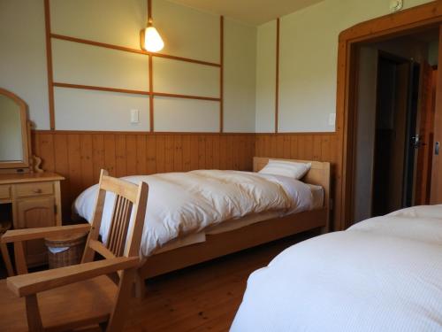 een slaapkamer met 2 bedden, een tafel en een spiegel bij ポロト案内舎 in Hamanaka