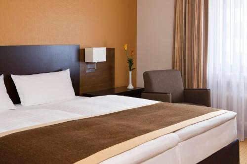 
a hotel room with a white bed and white comforter at Trans World Hotel Donauwelle in Linz
