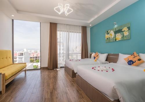Habitación de hotel con 2 camas y sofá en Raon Danang Beach - STAY 24H en Da Nang