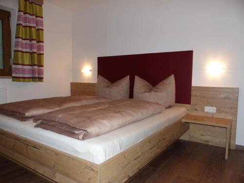 Schlafzimmer mit einem großen Bett mit einem Kopfteil aus Holz in der Unterkunft Haus Resi in Berwang