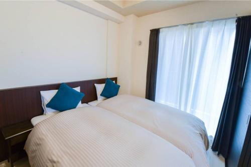 a bedroom with a bed with blue pillows and a window at momo premium 804 in Sapporo