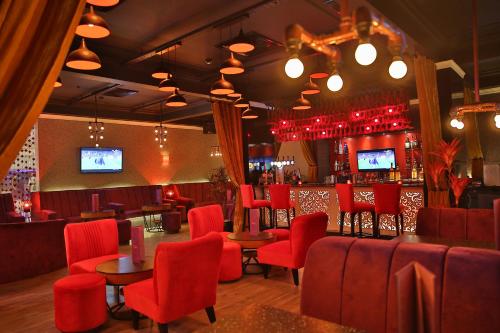 a restaurant with red chairs and a bar with televisions at Park Plaza, Ludhiana in Ludhiana