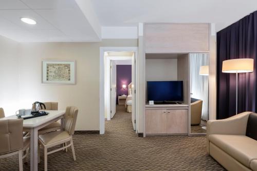 a hotel room with a living area with a tv and a couch at Holiday Inn Naples by IHG in Naples