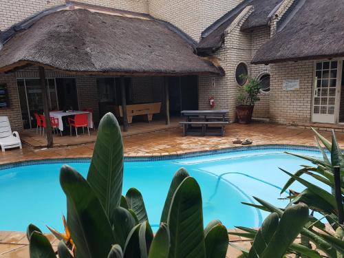 a house with a swimming pool and a thatch roof at Lion's Guesthouse and The Buck&Lion Restaurant in Groblersdal