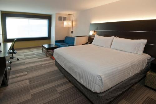 a hotel room with a bed and a blue chair at Holiday Inn Express & Suites Johnstown, an IHG Hotel in Johnstown