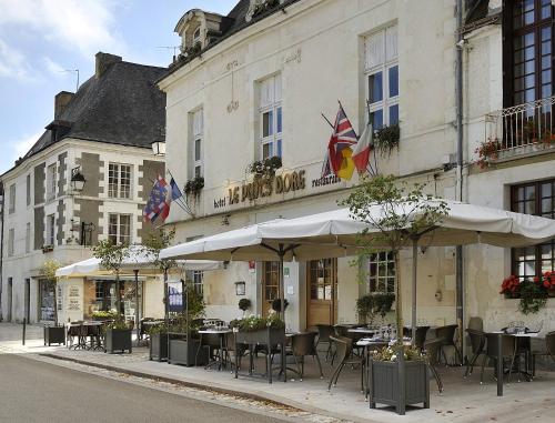 a restaurant with tables and umbrellas in front of a building at Logis Hôtel Restaurant Le Puits Doré in Richelieu