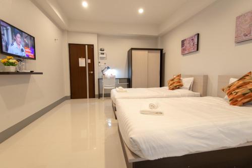 two beds in a room with a tv on the wall at J2 Residence Chiang Rai in Chiang Rai