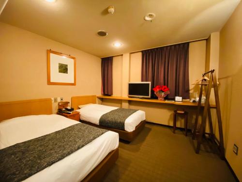 a hotel room with two beds and a television at Hotel Free Style in Kofu