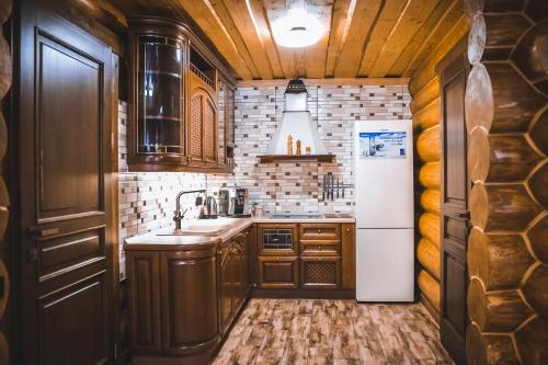a kitchen with wooden cabinets and a white refrigerator at Tatova Hata in Yablunytsya