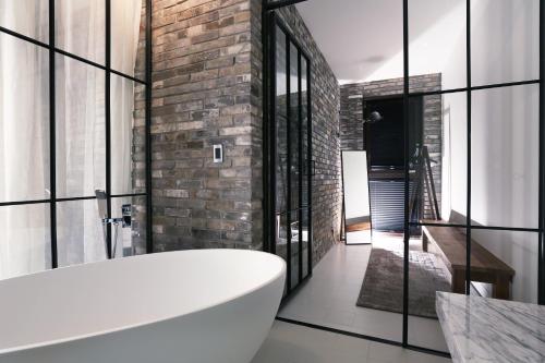 a bathroom with a white tub and a brick wall at Boutique Hotel Loft in Seoul