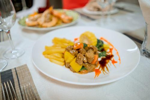 a white plate of food with french fries on a table at Bella Vita Hotel in Long Hai