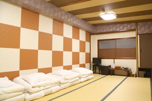 a room with several beds lined up against a wall at Tokyo Ueno New Izu Hotel in Tokyo