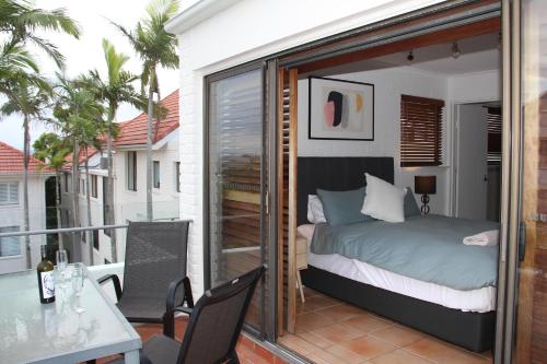 Habitación con cama y balcón con mesa. en Haven on Noosa Hill - sunset views, pools, spa en Noosa Heads