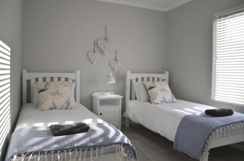 two beds in a white room with two pillows at Beach Blessings, Fun in the sun in Stilbaai