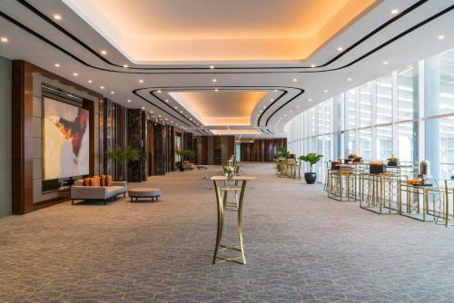 a hallway in a building with a lobby with windows at Swissôtel Jakarta PIK Avenue in Jakarta