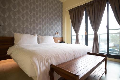 a bedroom with a large bed with a bench next to a window at Chance Villa 262 in Jiaoxi