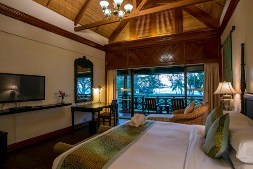 a bedroom with a bed and a desk and a television at Nexus Resort & Spa Karambunai in Kota Kinabalu