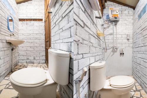 two toilets sitting next to each other in a bathroom at Mettaloka Guesthouse in Magelang