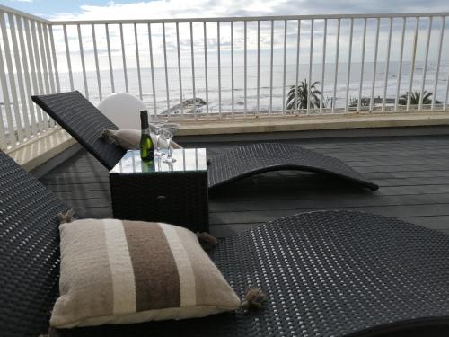 a balcony with a table and chairs and a bottle of wine at Ático con Fantásticas Vistas al Mar y la iglesia in Sitges