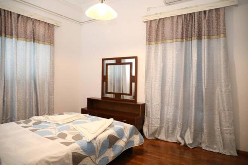 a bedroom with a bed and a mirror and curtains at Andreas Naxos Center - House in Naxos Chora