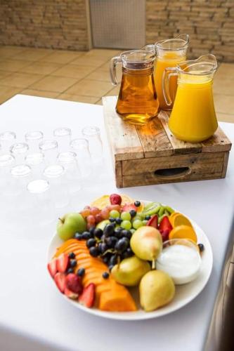 a plate of fruit on a table with two glasses of juice at Appledew Guesthouse in Standerton