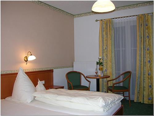 Landgasthof-Hotel Hammermühle في دوناوستاف: غرفة نوم بسرير وطاولة وكراسي